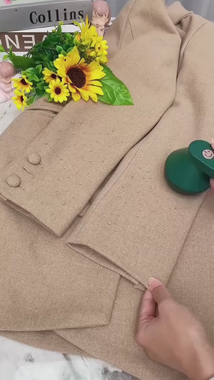 Beige coat with a hand holding a green object and sunflower decorations.