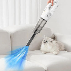 Person using a handheld vacuum cleaner on a sofa with a cat nearby